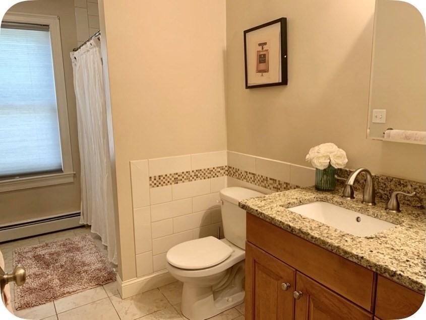 54 Desoto Road, Unit 3 Boston, MA 02132 - Photo 4 of 5 a bathroom with a granite countertop toilet sink and mirror