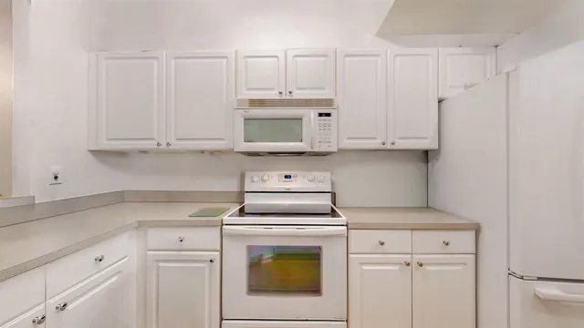 a kitchen with white cabinets and white appliances