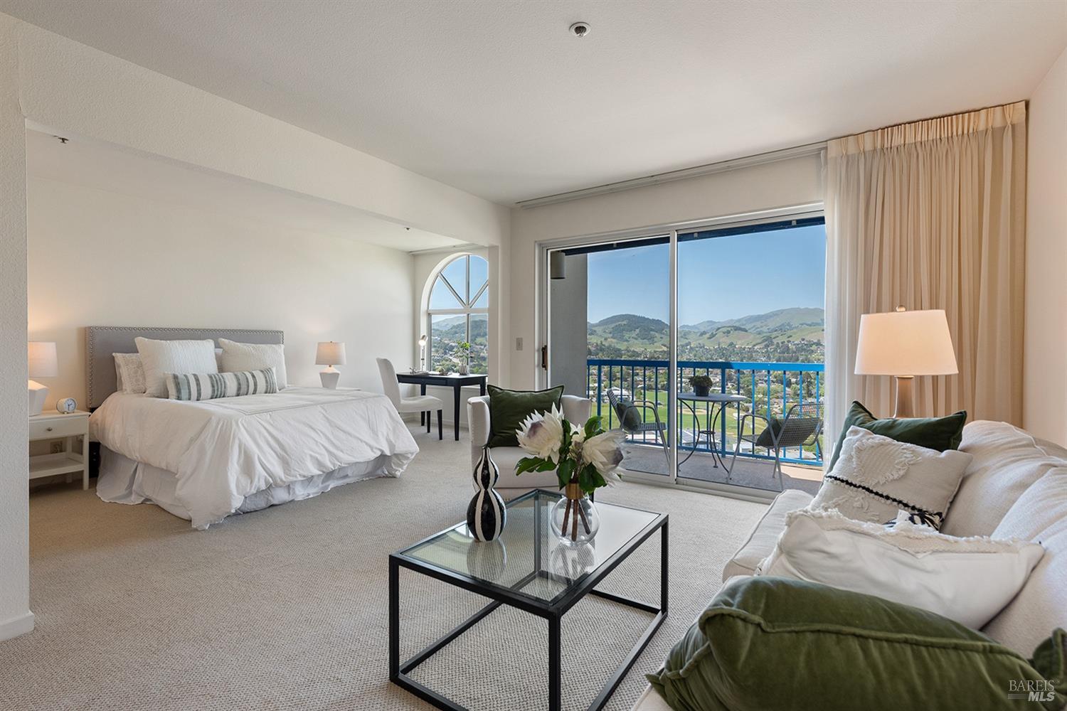 a spacious bedroom with a bed and glass window