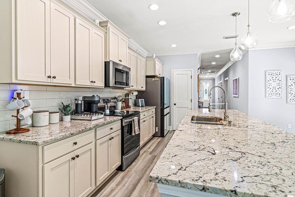 57 5th Street Shalimar, FL 32579 - Photo 5 of 30 a kitchen with stainless steel appliances granite countertop a stove top oven a sink a refrigerator and white cabinets with wooden floor
