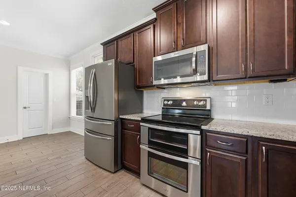 a kitchen with a stove a window and wooden floor