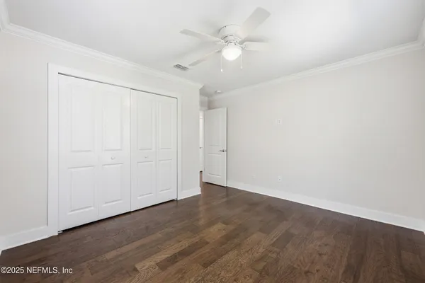 an empty room with wooden floor and fan
