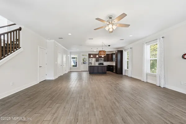 an empty room with wooden floor chandelier and windows