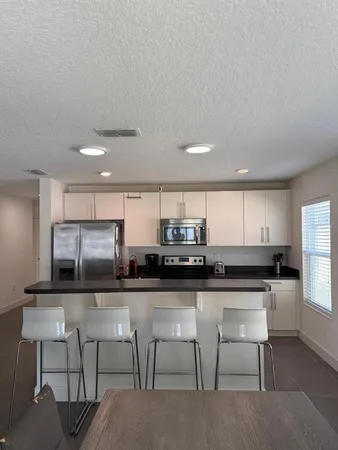 a kitchen with stainless steel appliances kitchen island granite countertop a table chairs microwave and sink