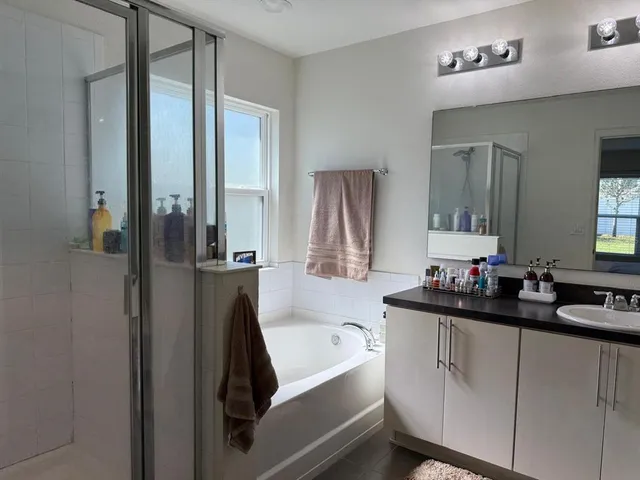 a bathroom with a double vanity sink a mirror and a bathtub