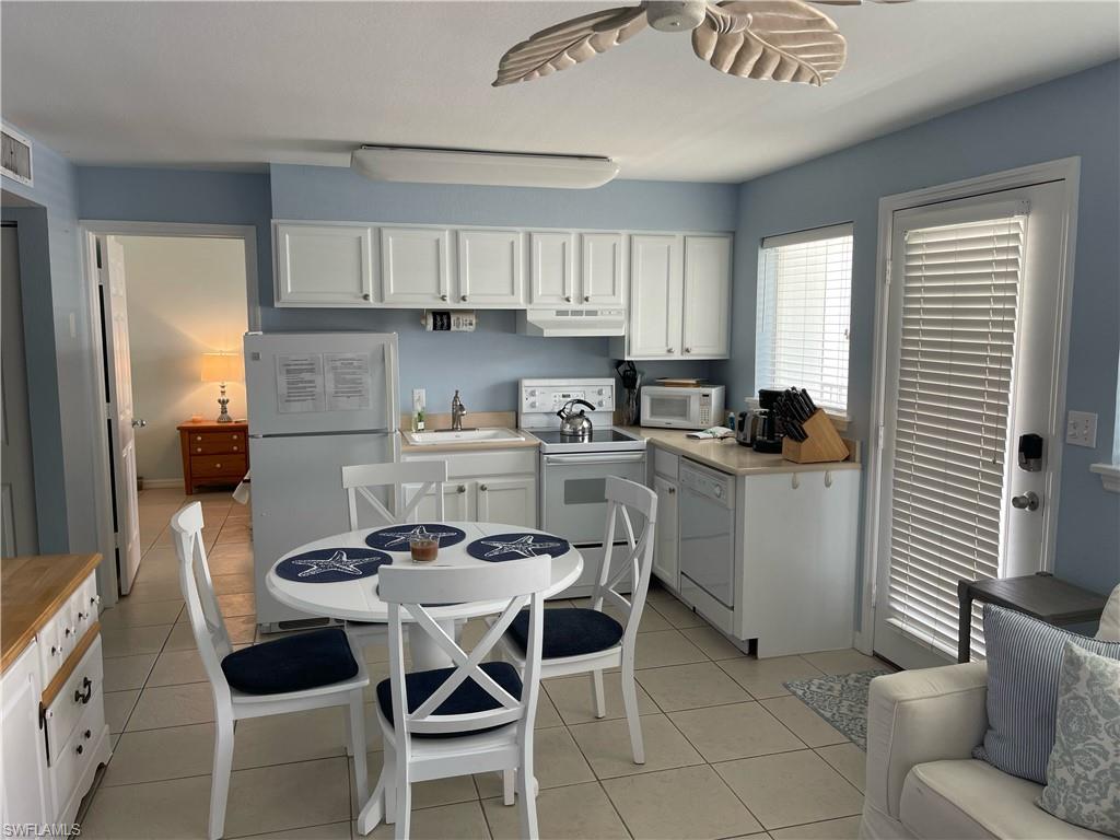 175 5th Avenue South, Unit 9 Naples, FL 34102 - Photo 3 of 19 a kitchen with a dining table chairs cabinets and stainless steel appliances