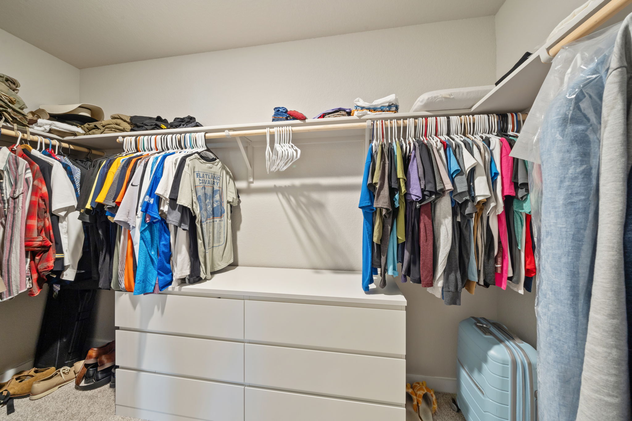 1117 Tipton Street Georgetown, TX 78633 - Photo 25 of 40 White-painted walk-in closet featuring extensive built-in shelving, multiple hanging rods, and a six-drawer dresser unit