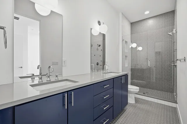 a bathroom with a double vanity sink toilet mirror and shower