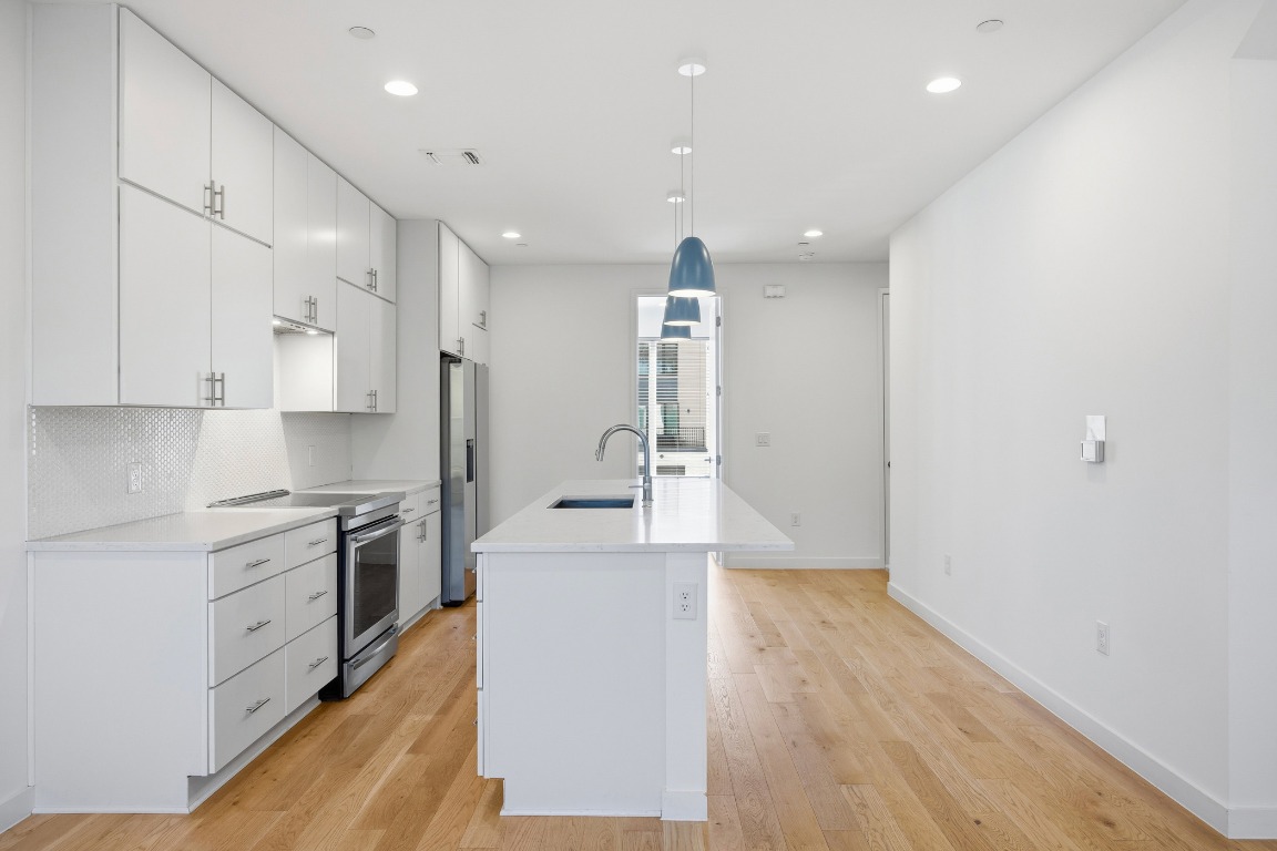 6020 Springdale Road, Unit 12 Austin, TX 78723 - Photo 4 of 28 a large kitchen with stainless steel appliances a large counter top a stove and a wooden floors