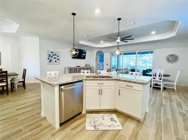 a kitchen with kitchen island granite countertop a stove a sink a dining table and chairs with wooden floor