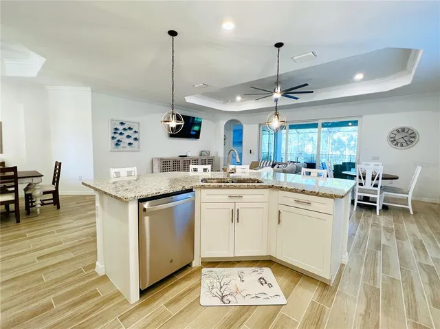 a kitchen with kitchen island granite countertop a stove a sink a dining table and chairs with wooden floor