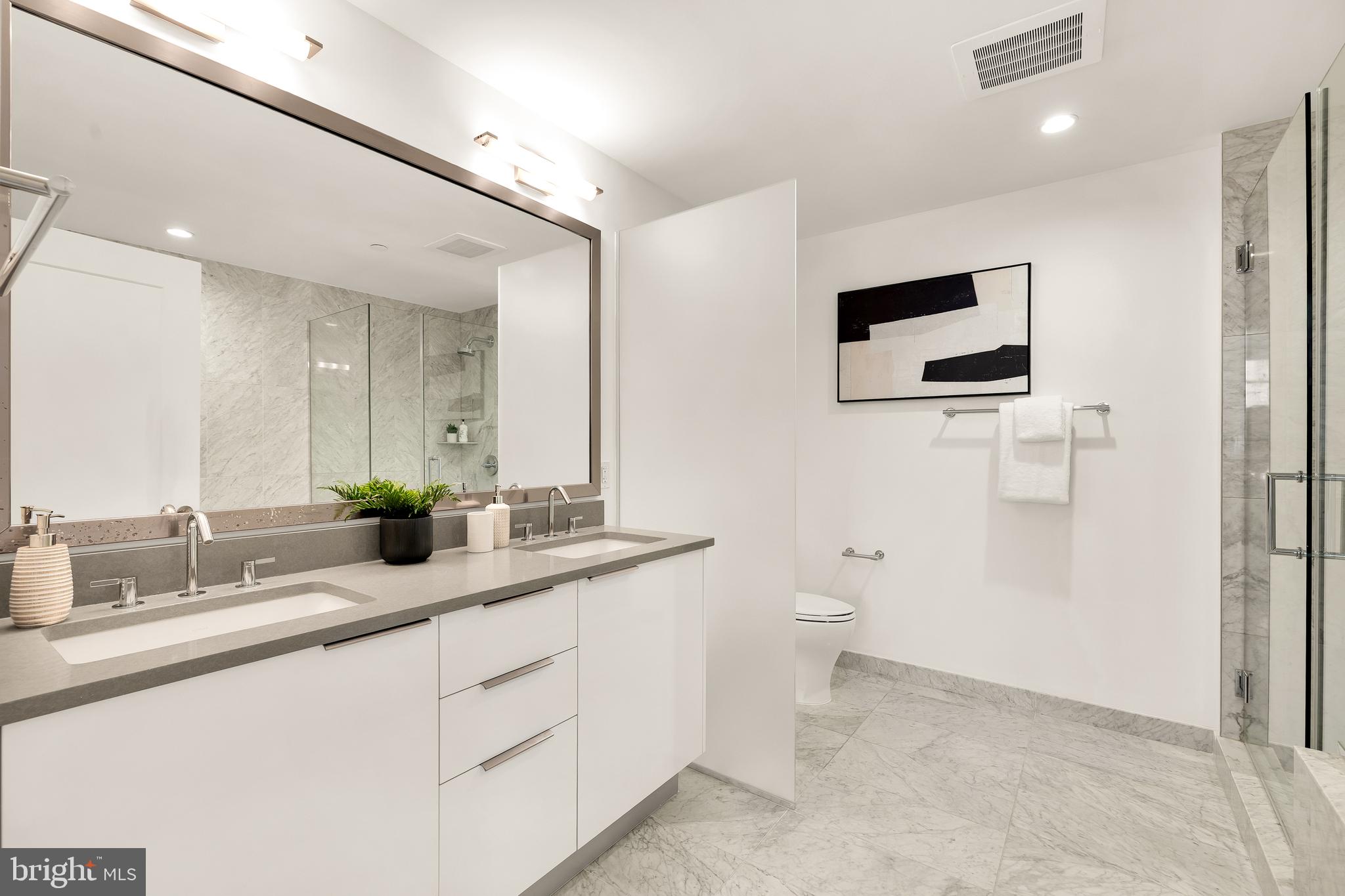 45 Sutton Square Southwest, Unit 906 Washington, DC 20024 - Photo 28 of 50 a bathroom with a double vanity sink a toilet and a mirror