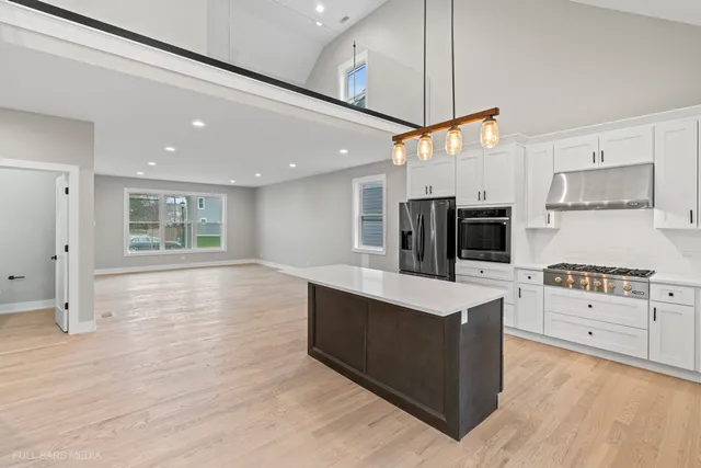 a large kitchen with stainless steel appliances kitchen island granite countertop a stove a sink and a refrigerator