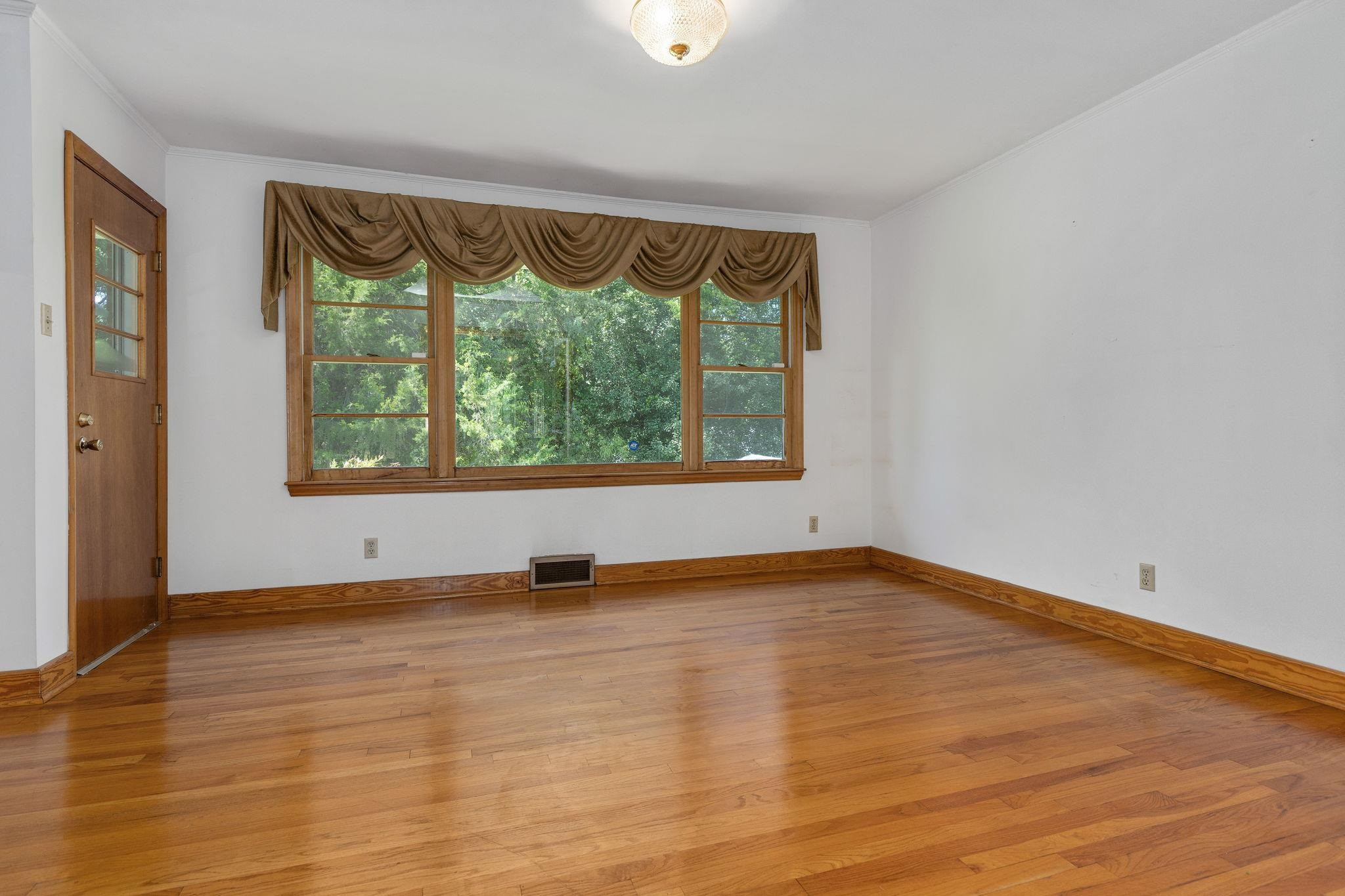 1309 Alpha Road Henderson, NC 27536 - Photo 9 of 26 a view of an empty room with a window and wooden floor