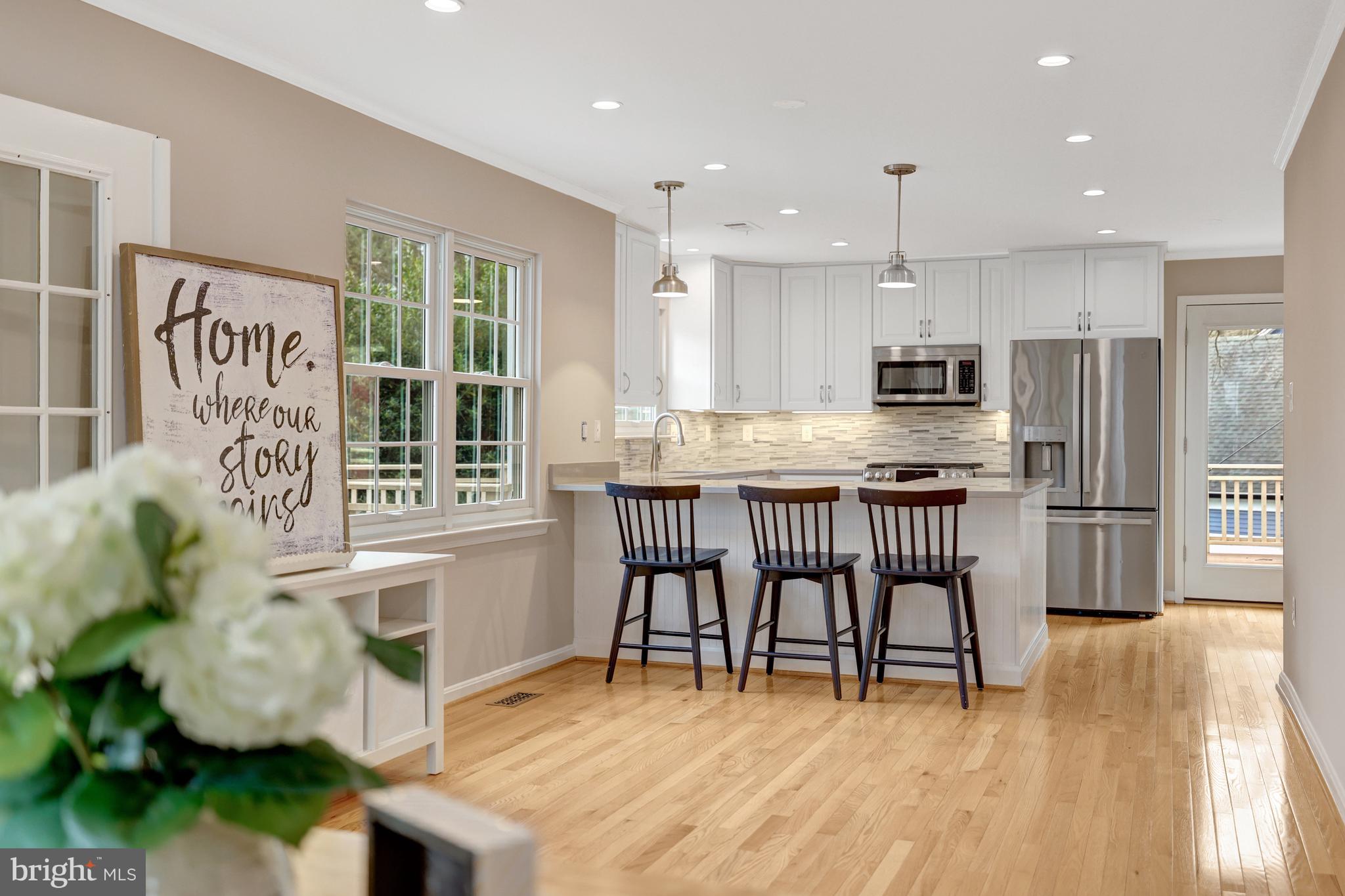 1215 Bishopsgate Way Reston, VA 20194 - Photo 4 of 41 a kitchen with stainless steel appliances kitchen island granite countertop a refrigerator a stove a sink a dining table and chairs with wooden floor
