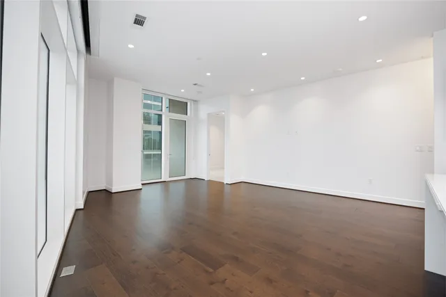 a view of a hallway with wooden floor and a bathroom