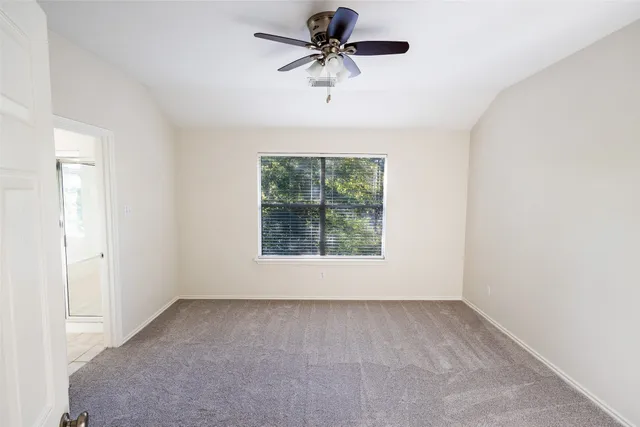 an empty room with a ceiling fan and a window