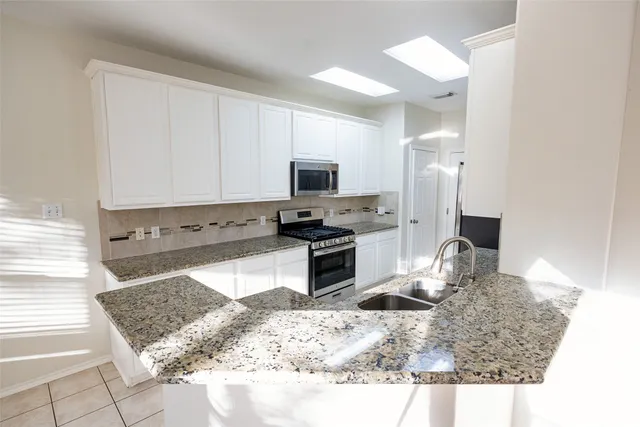 a kitchen with a sink a counter top space appliances and cabinets