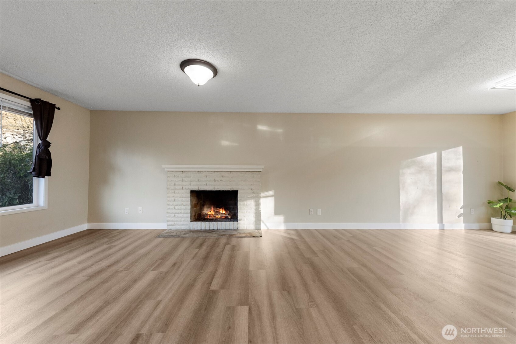 12727 Southeast 191st Place Renton, WA 98058 - Photo 2 of 23 an empty room with wooden floor a fireplace and windows
