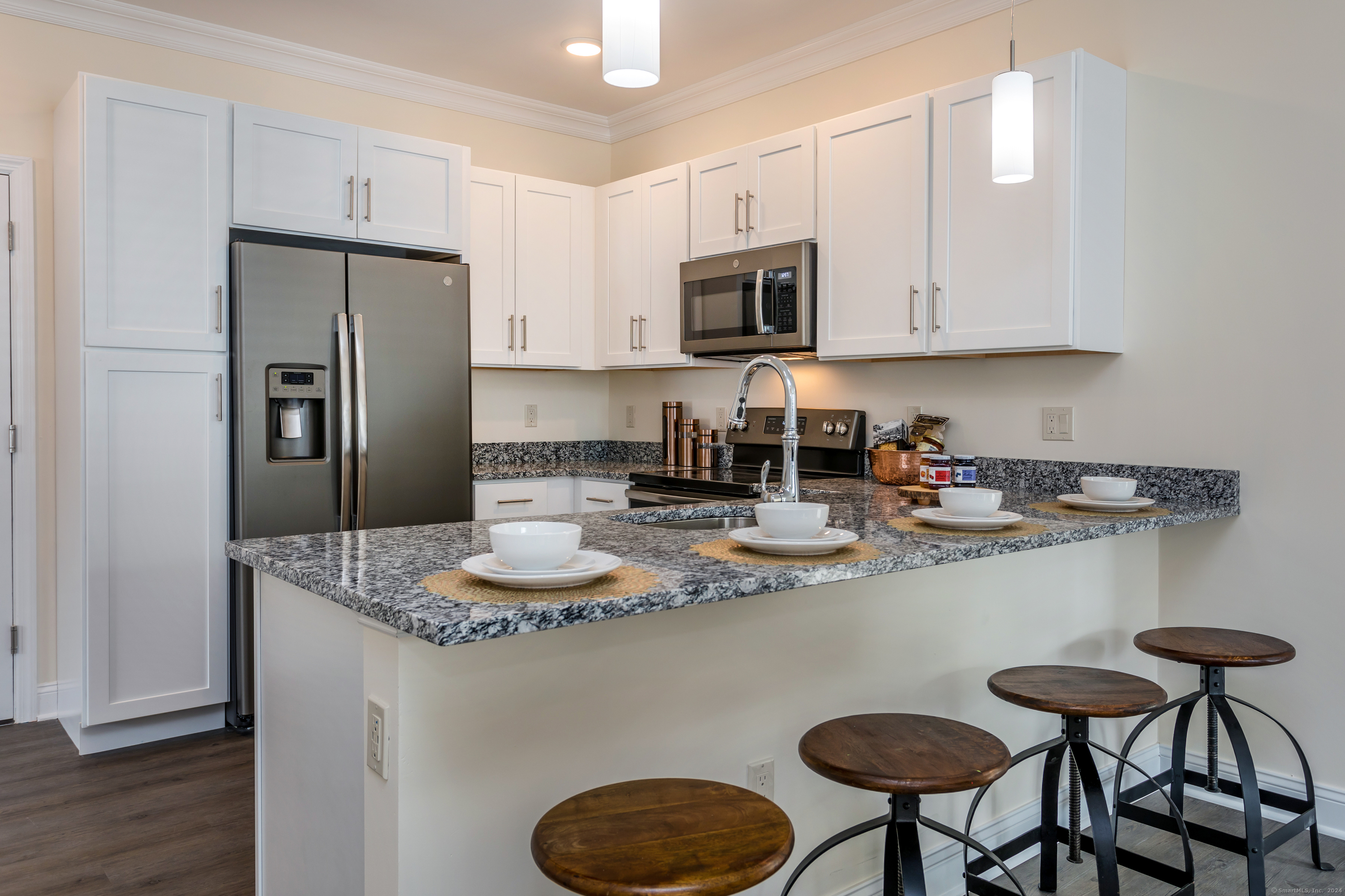 48 Stony Hill Road, Unit B 305 Bethel, CT 06801 - Photo 3 of 11 a kitchen with stainless steel appliances granite countertop a sink a stove a refrigerator and white cabinets with wooden floor