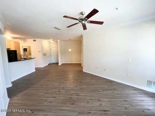 a view of a room with a ceiling fan and wooden floor