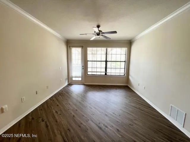 an empty room with wooden floor chandelier and windows