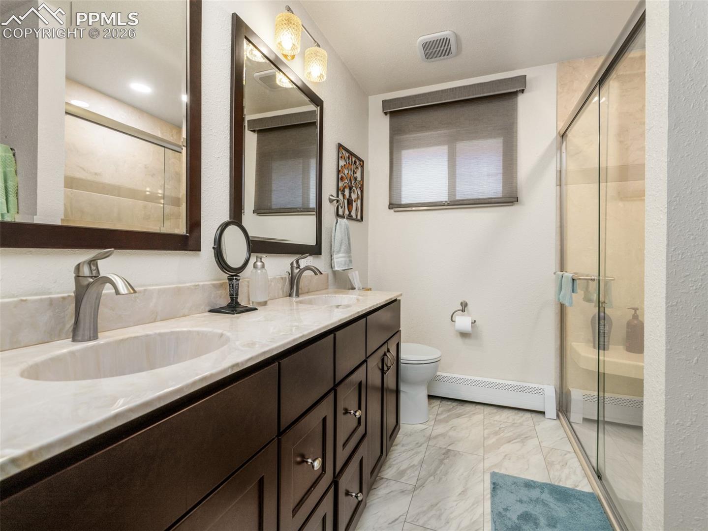 20 Robertson Road Pueblo, CO 81001 - Photo 16 of 39 Upgraded bathroom featuring a baseboard heating unit, a walk-in shower, double vanity, light tile finish floors, and a textured wall