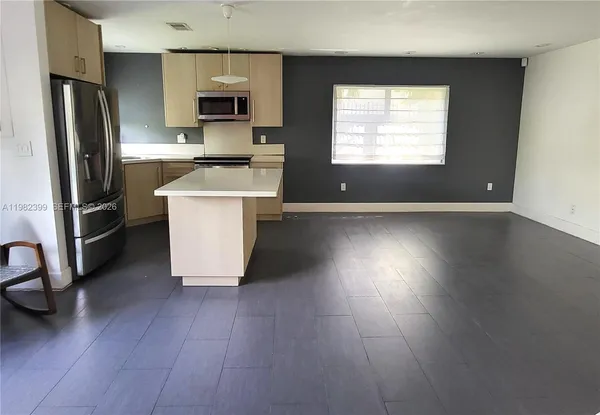 a kitchen with stainless steel appliances granite countertop a stove a refrigerator a sink a microwave and wooden floor