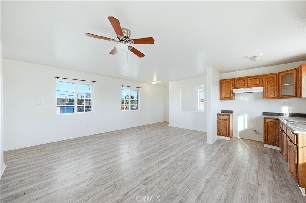 10929 Compton Avenue Los Angeles, CA 90059 - Photo 18 of 29 an empty room with wooden floor a ceiling fan and windows