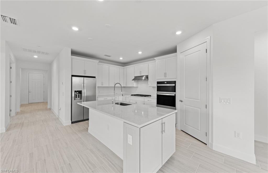 15707 Northridge Road Punta Gorda, FL 33982 - Photo 5 of 21 a kitchen with white cabinets and stainless steel appliances