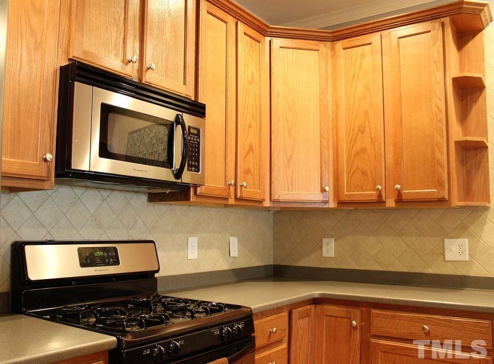 7304 Caversham Way Raleigh, NC 27617 - Photo 4 of 22 a kitchen with stainless steel appliances granite countertop white cabinets and a stove top oven