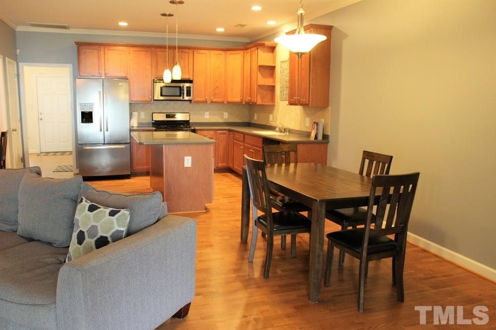 7304 Caversham Way Raleigh, NC 27617 - Photo 9 of 22 a kitchen with stainless steel appliances granite countertop a stove a sink a microwave a dining table and chairs with wooden floor