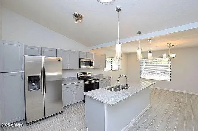 a kitchen with stainless steel appliances a sink a stove a refrigerator and cabinets
