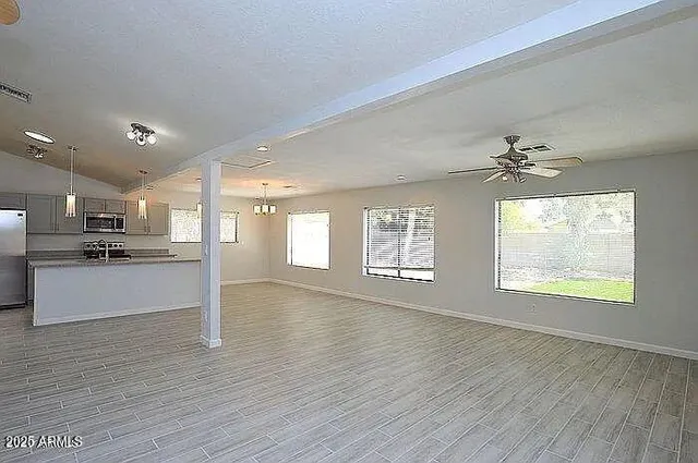 a view of an empty room with window and wooden floor