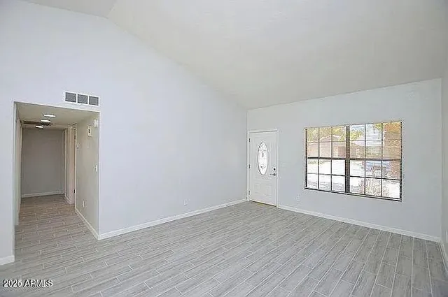 an empty room with wooden floor and windows