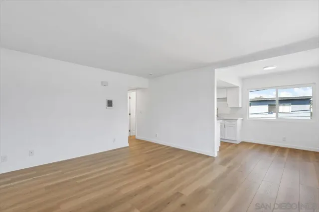 a view of empty room with wooden floor and window