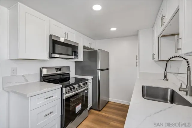 a kitchen with stainless steel appliances white cabinets a sink and a stove