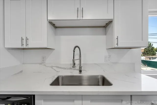 a kitchen with granite countertop white cabinets and a sink