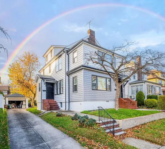 a view of a white house next to a yard with large trees