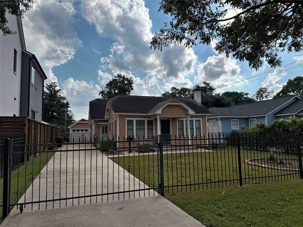 a view of a brick house with a small yard plants and large trees