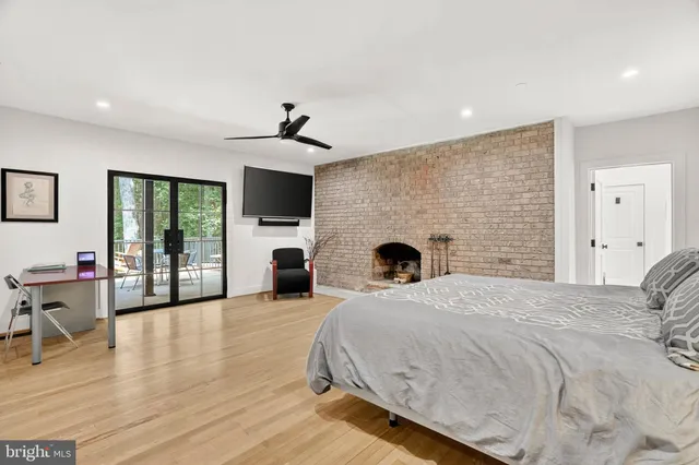 a bedroom with a bed a desk and chair with wooden floor