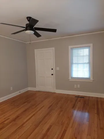 a view of an empty room with wooden floor and a window