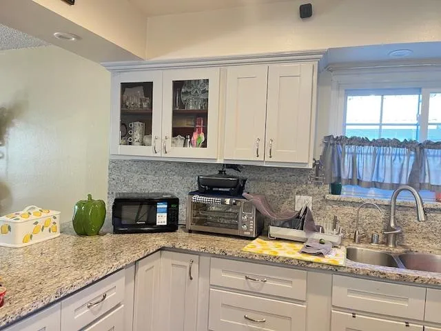 a kitchen with granite countertop stainless steel appliances sink stove and cabinets