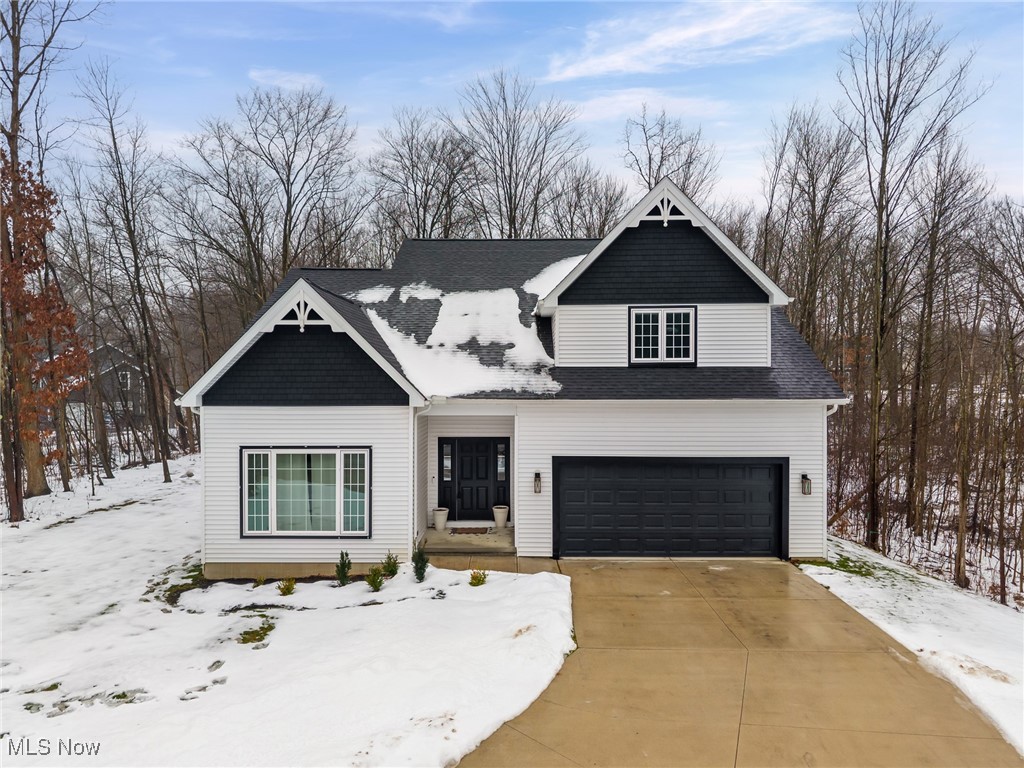 View of front facade with an attached garage, roof with shingles, and concrete driveway