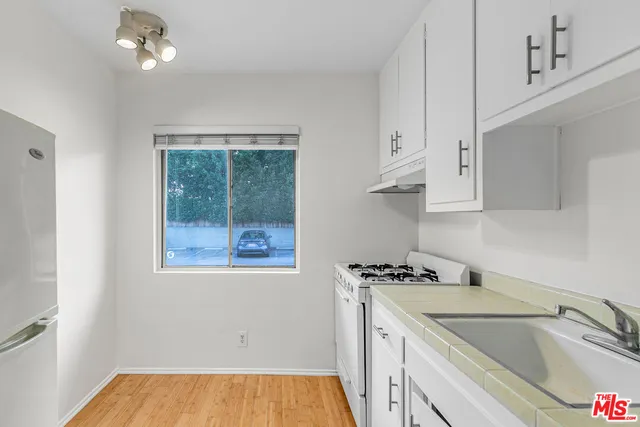 a kitchen with white cabinets a sink a window and stainless steel appliances