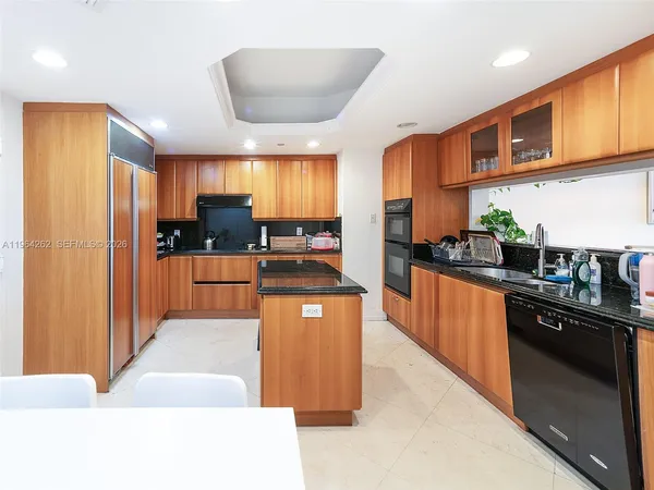 a large kitchen with stainless steel appliances kitchen island granite countertop a refrigerator a sink a stove top oven and a dining table