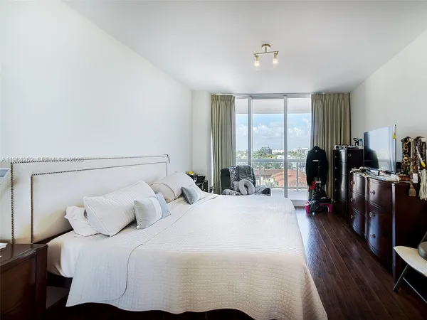 a bedroom with a balcony a bed and a large window