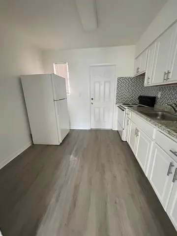 a kitchen with granite countertop white cabinets and wooden floor