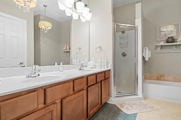 a bathroom with a sink double vanity granite tub shower and a mirror