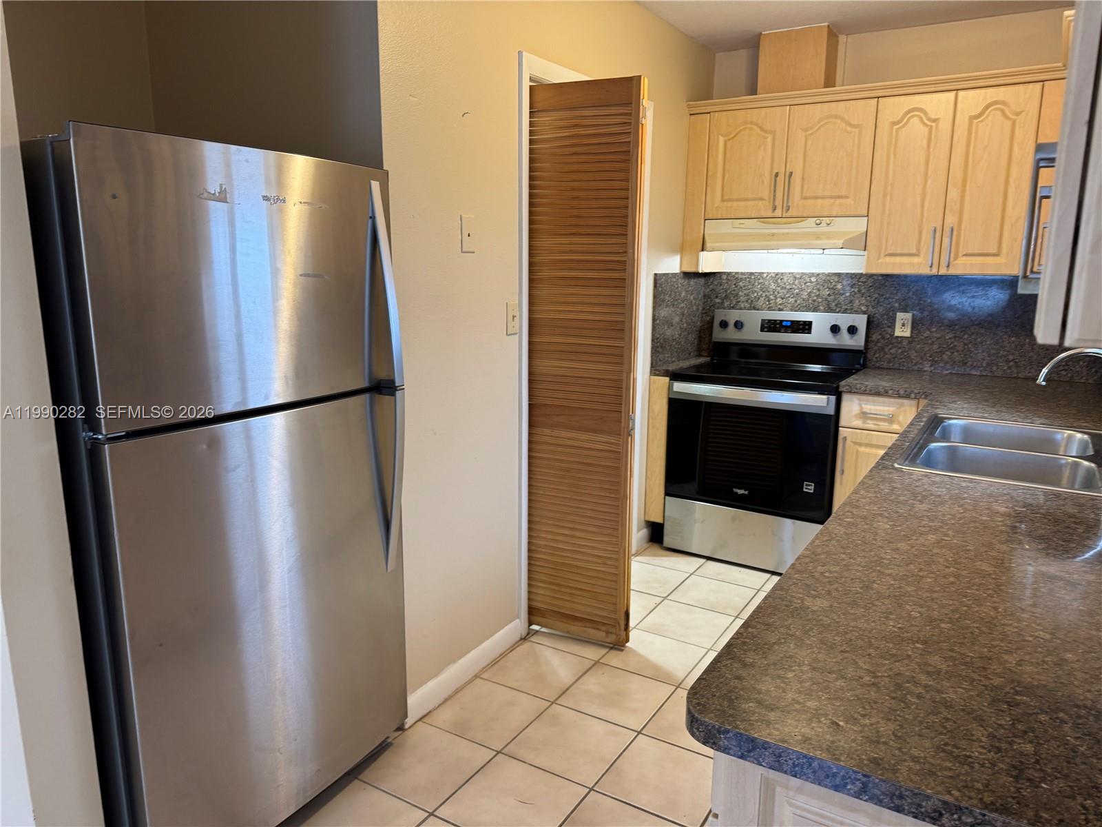 1124 Northwest 3rd Street Miami, FL 33128 - Photo 2 of 5 a kitchen with stainless steel appliances granite countertop a refrigerator a stove and a sink